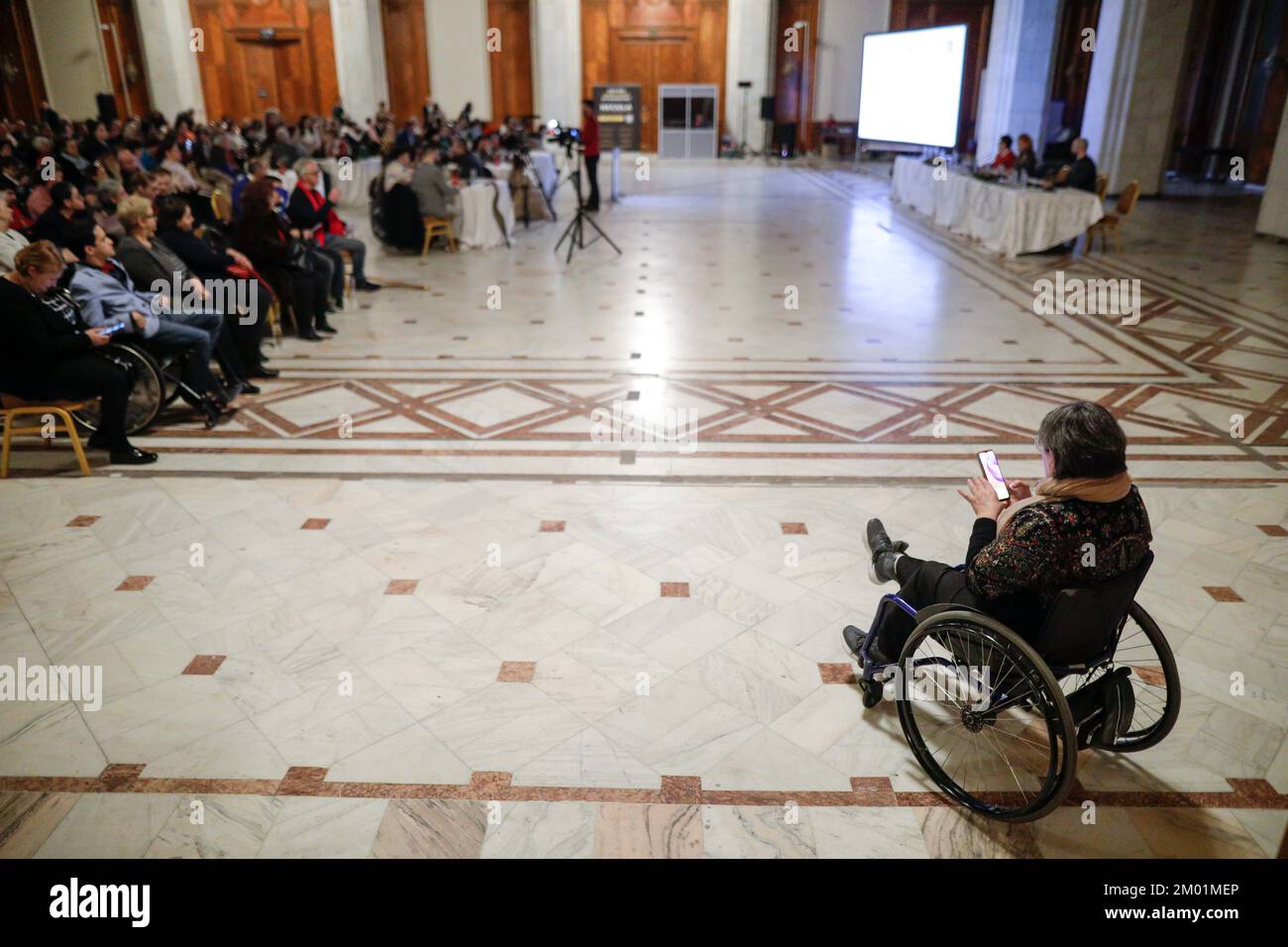 Shallow depth of field (selective focus) details with a woman in a wheelchair during a convention. Stock Photo