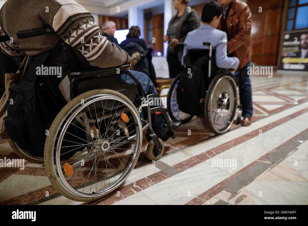 Shallow depth of field (selective focus) details with a man in a wheelchair during a convention. Stock Photo