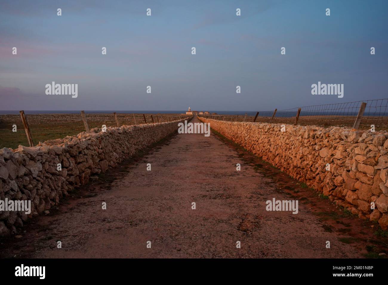 Dry stone wall on road to Punta Nati Lighthouse at sunset on the Balearic island of Menorca, Spain. Stock Photo