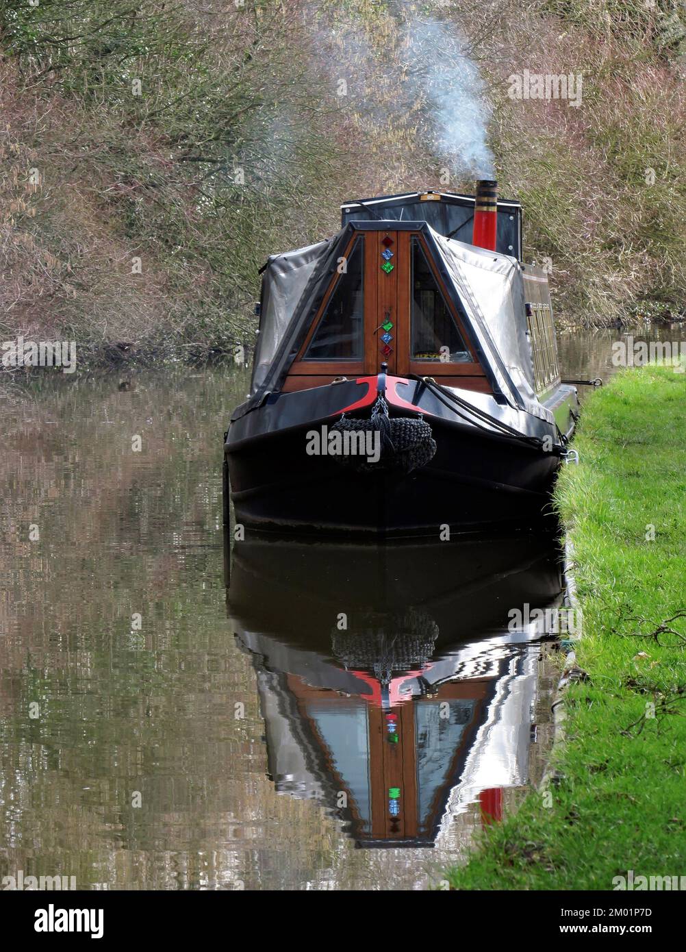 Narrowboat moored in winter with smoke rising from chimney on the Staffordshire and Worcester canal at Great Haywood on a sunny day in winter. Stock Photo