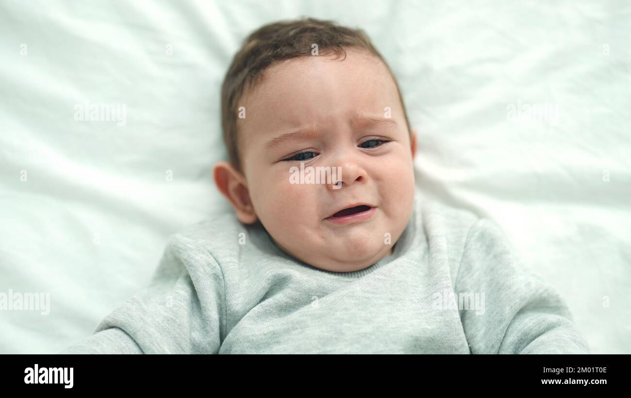 Adorable hispanic baby lying on bed crying at bedroom Stock Photo Alamy