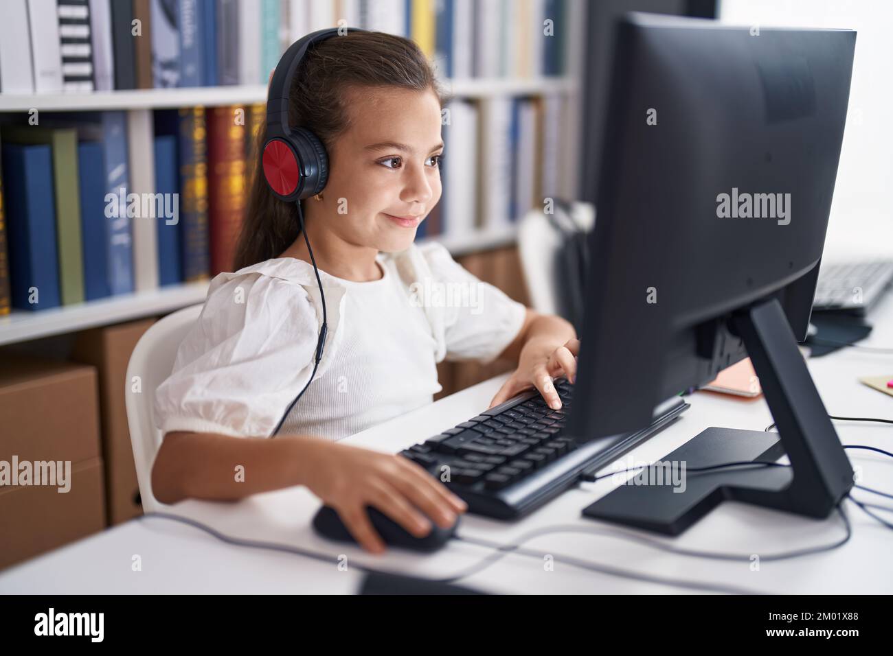 Adorable hispanic girl student using computer and headphones sitting on ...