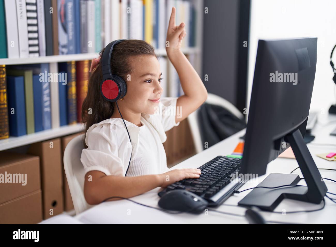 Adorable hispanic girl student using computer and headphones having ...
