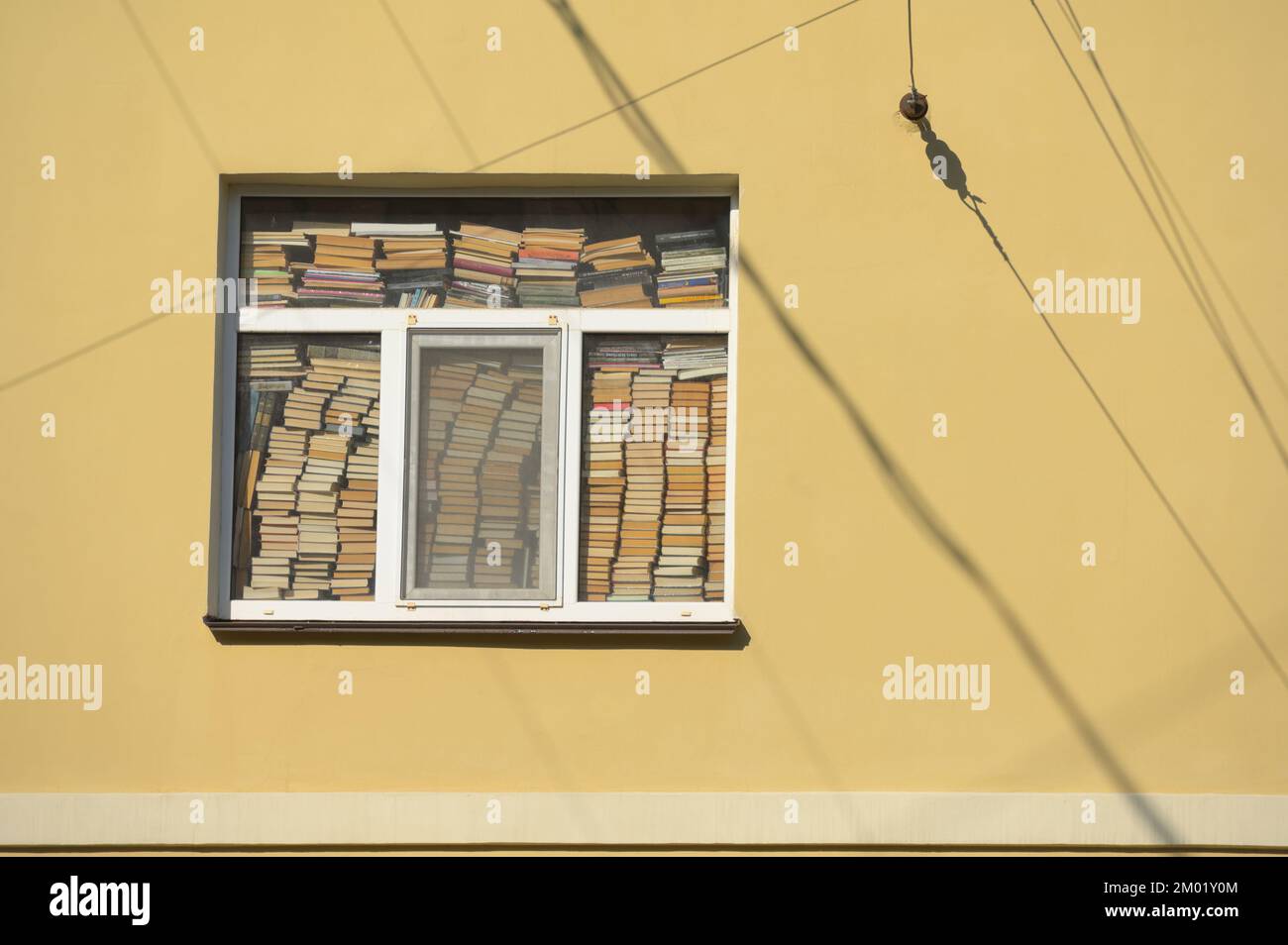 Stacks of books in a window of an apartment building Stock Photo
