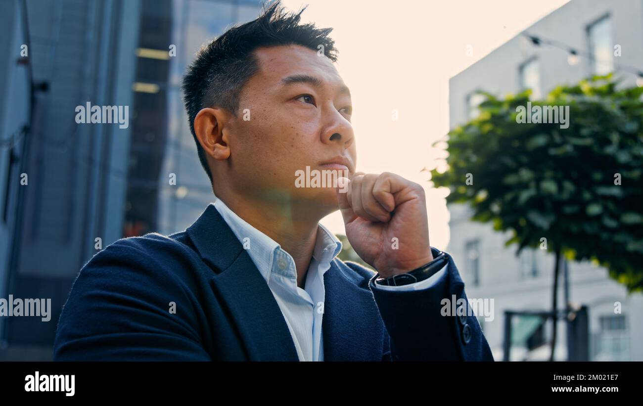 Dreaming alone thinking pensive 40s Asian Korean man puzzled confused thoughtful decision problem solution. Adult Chinese businessman entrepreneur Stock Photo