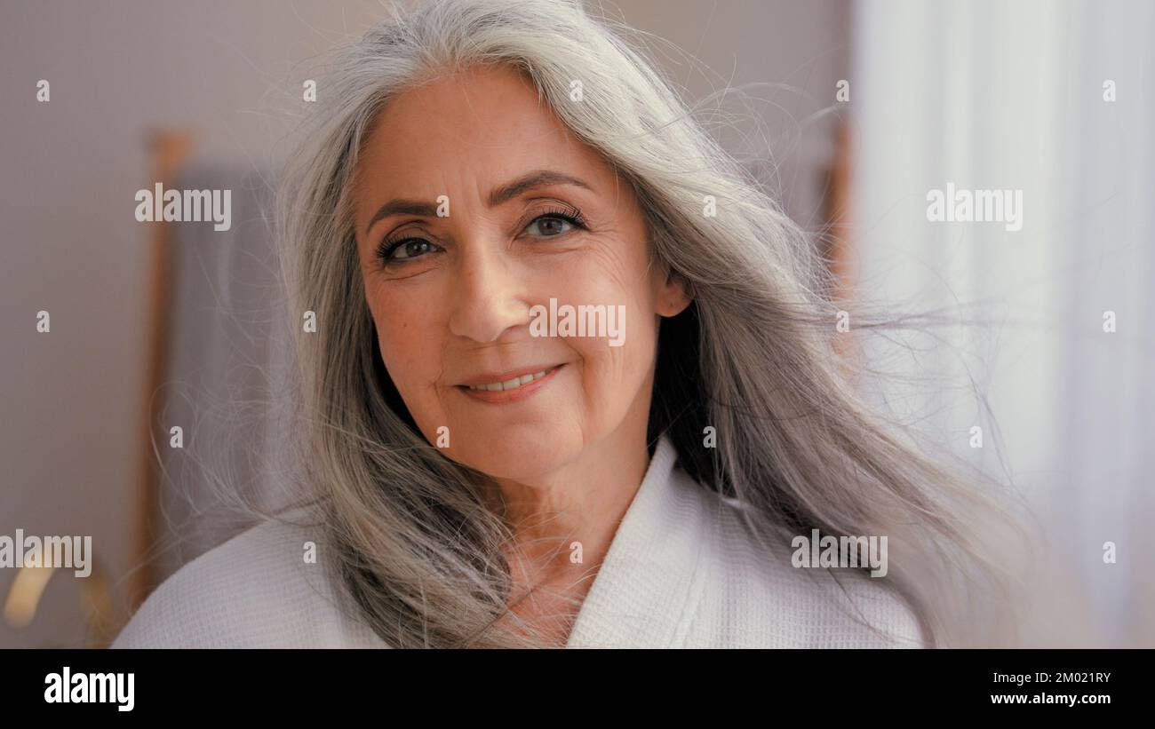 Headshot close up Caucasian gorgeous happy smiling middle-aged mature senior woman older 50s lady smile looking at camera pampering flying hair in Stock Photo