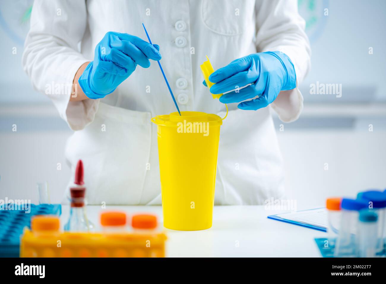 Throwing away medical waste in a hazardous waste container Stock Photo