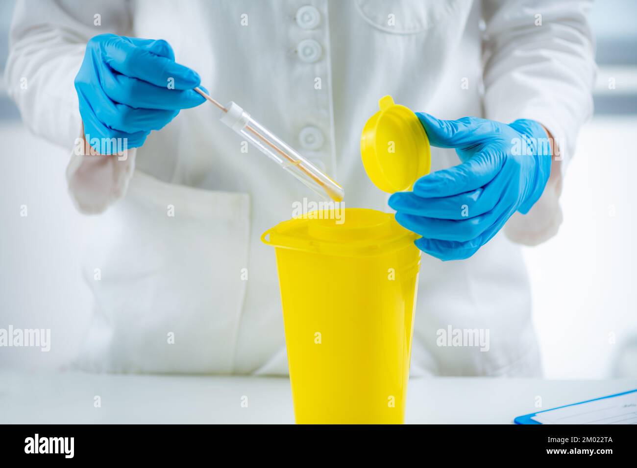 Throwing away medical waste in a hazardous waste container Stock Photo