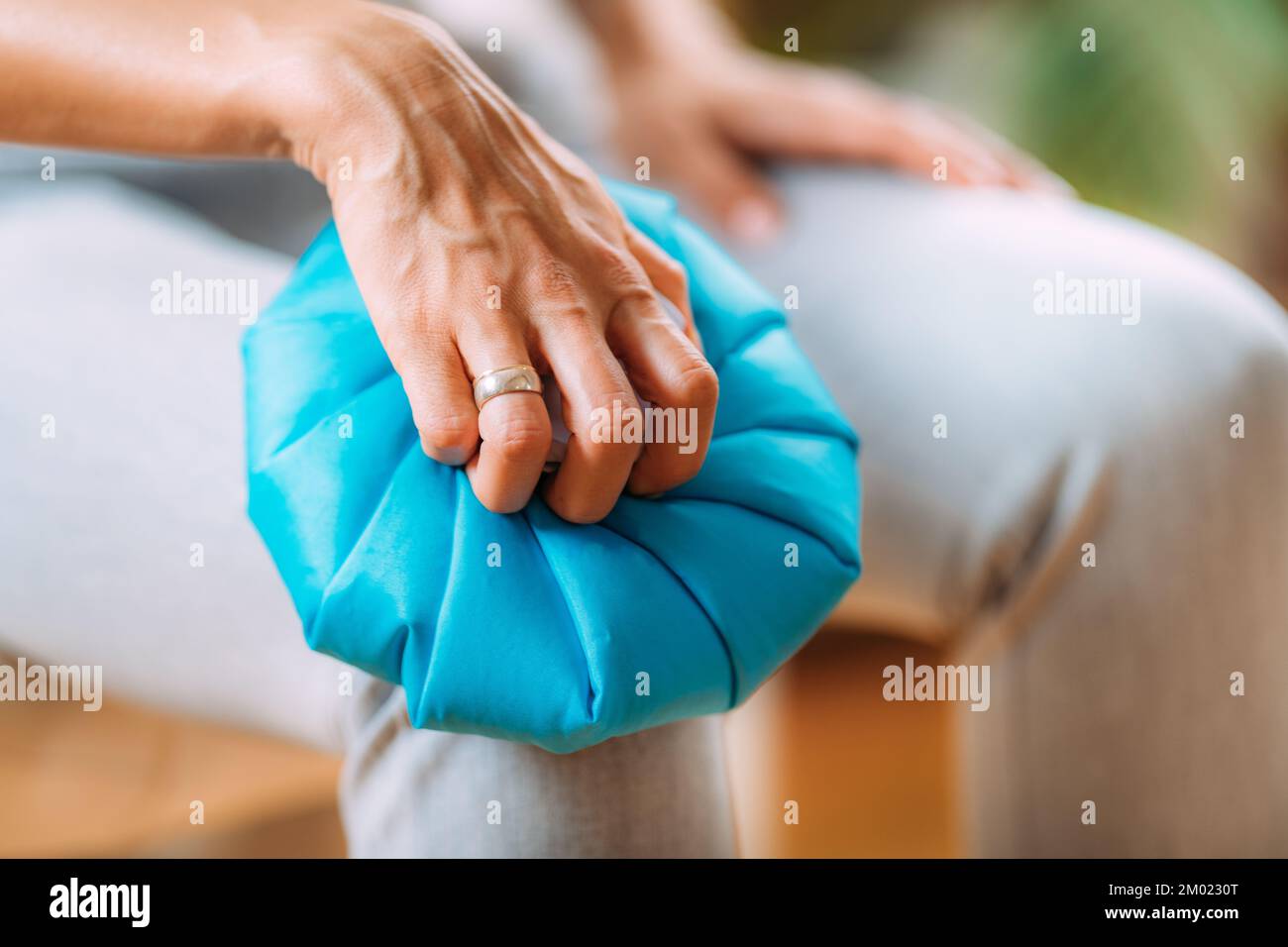 Woman holding an ice bag pack over a painful knee. Stock Photo