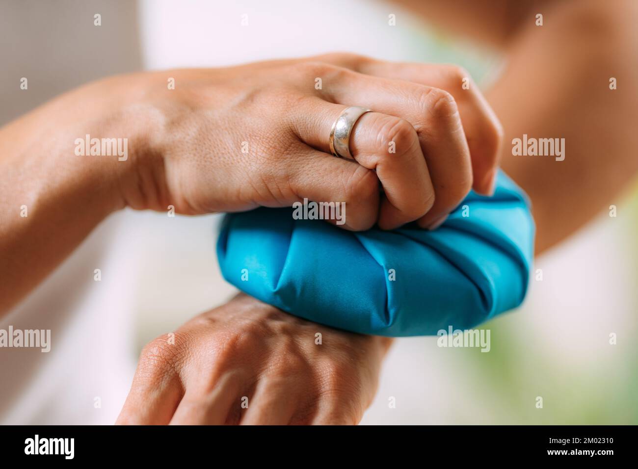 Woman holding ice bag compress on a painful wrist. Stock Photo