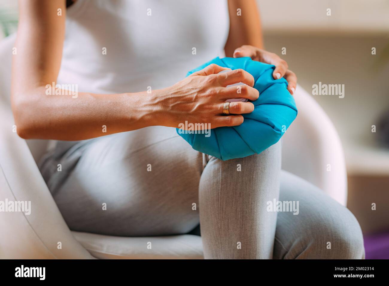 Woman holding a cold compress over her painful knee. Stock Photo
