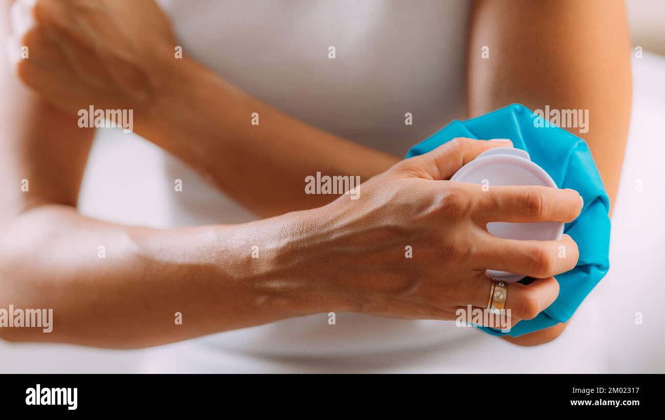Woman holding an ice bag compress on a painful elbow. Stock Photo