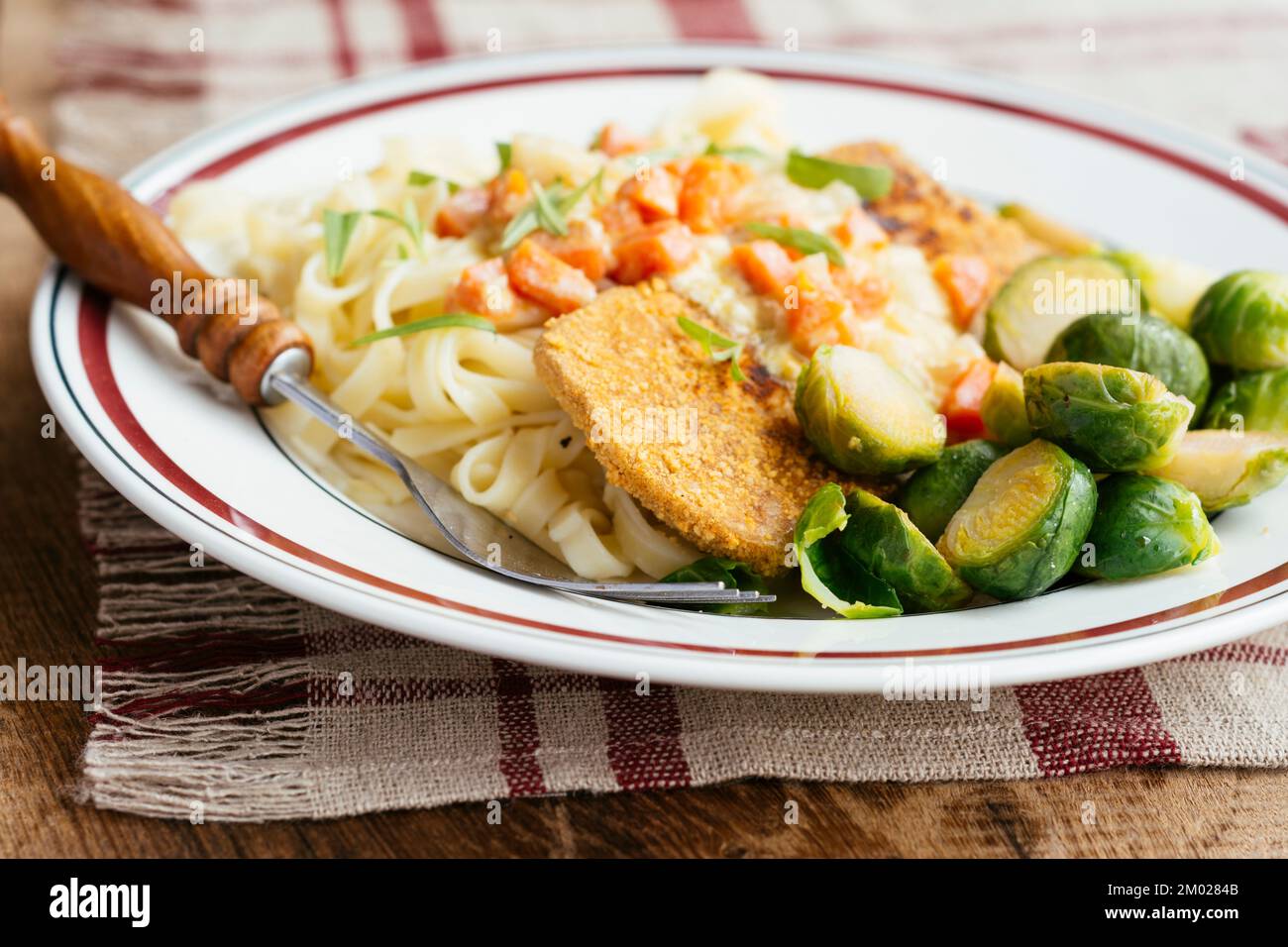 Vegetable Schnitzel on noodles with a creamy tarragon vegetable sauce and Brussels sprouts. Stock Photo
