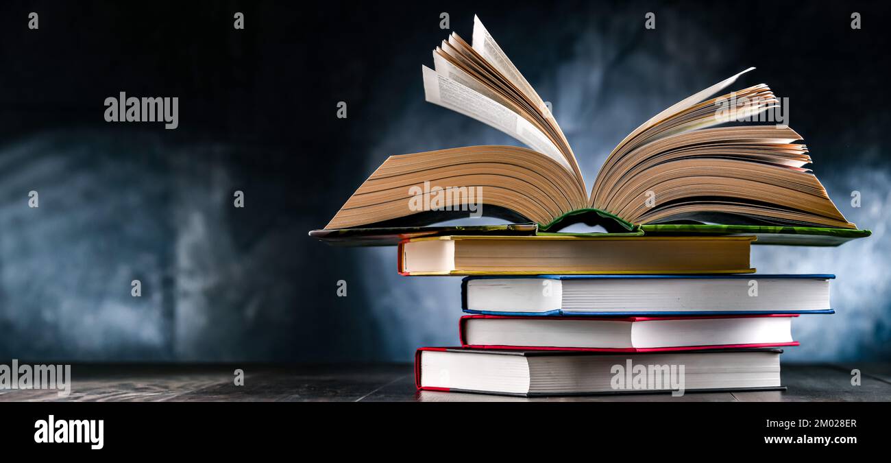 A composition with an open book lying on a stack of other books Stock Photo