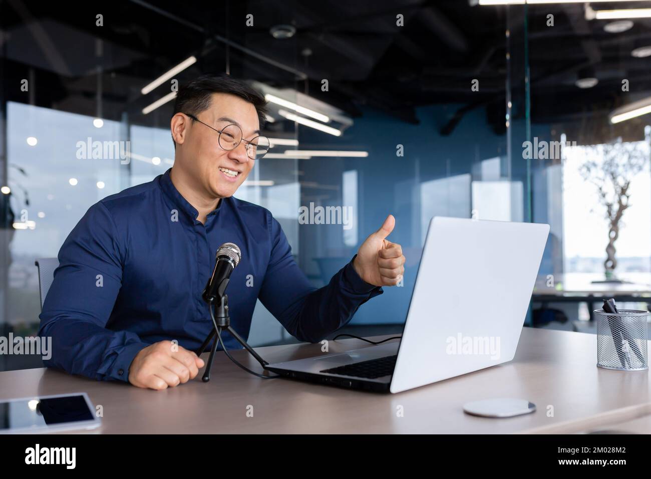 Successful Asian businessman mentor recording audio podcast, man in office using professional microphone for online radio and audio book recording. Stock Photo