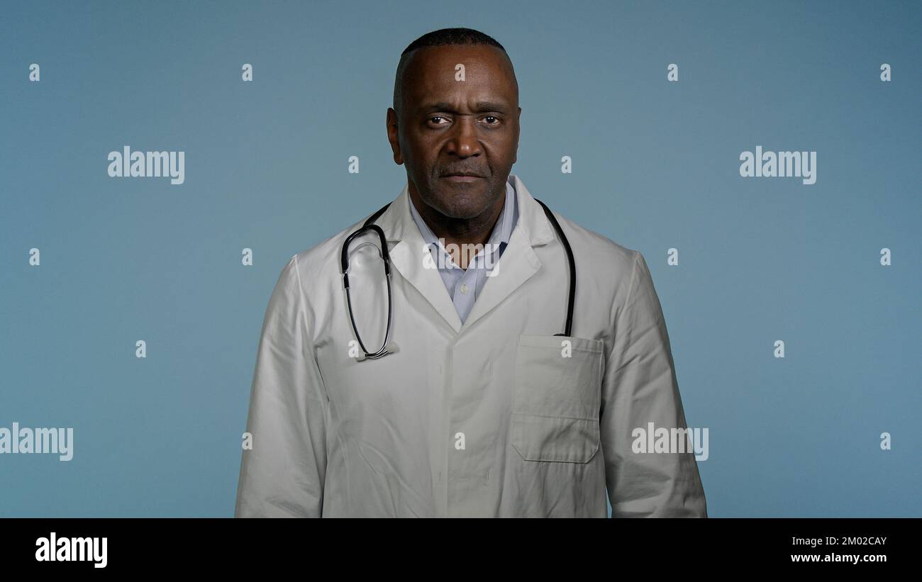 Mature confident happy doctor standing in gray background studio with arms crossed glad smiling african american man professional therapist physician Stock Photo