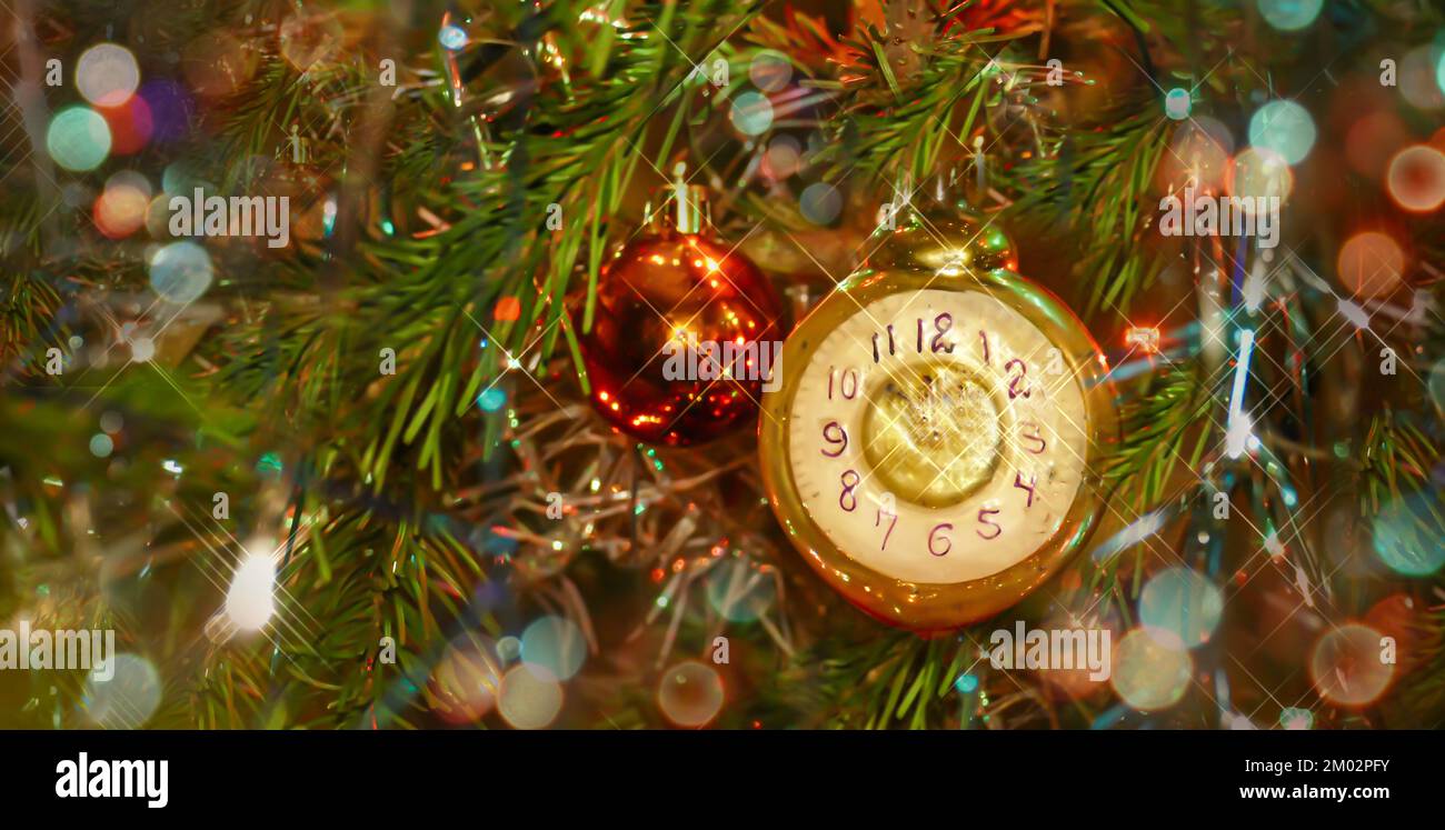 Christmas toy in the form of a clock on a festive tree shows the time 23.55 Stock Photo