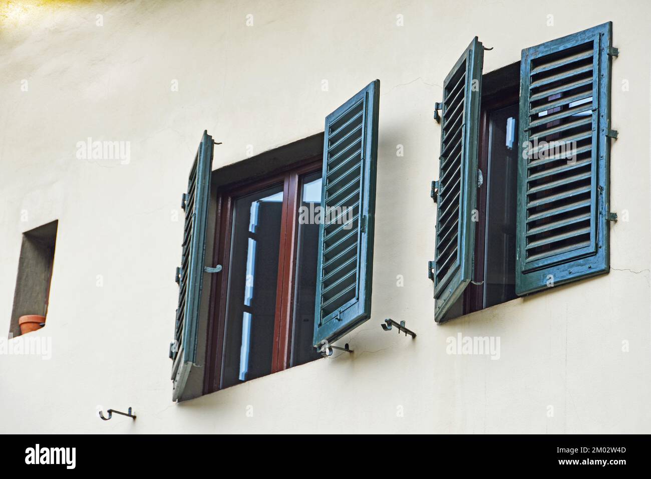 Two windows with dark green shutters on the facade of house #8 on the corner of Toscanella and Sprone in square Passera in Florence, Italy Stock Photo