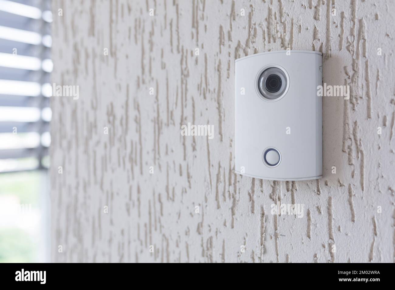A white electronic doorbell with a camera on the wall of the