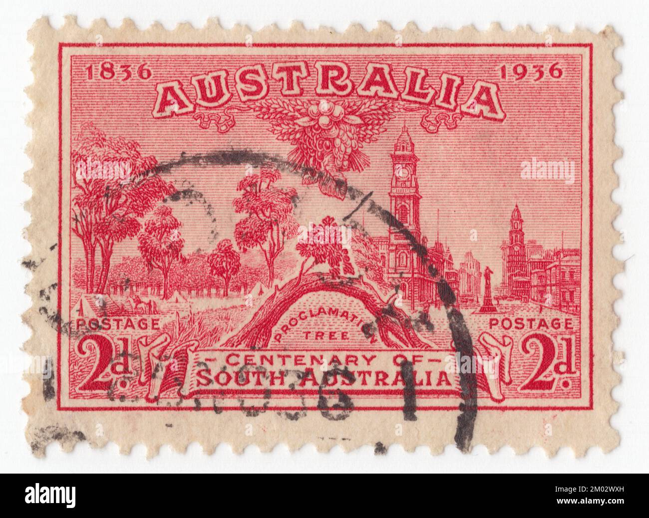 AUSTRALIA — 1936: An 2 pence red postage stamp depicting Proclamation Tree and view of Adelaide. Centenary of South Australia. The Old Gum Tree (also known as The Proclamation Tree) is a historic site in Glenelg North, South Australia. Near this tree on 28 December 1836, the British governor John Hindmarsh delivered the proclamation announcing the establishment of Government of the colony of South Australia. A ceremony is held each year at the site on Proclamation Day, with the current Governor reading out Hindmarsh's original speech. The tree itself, probably a red gum, had died by 1907 Stock Photo