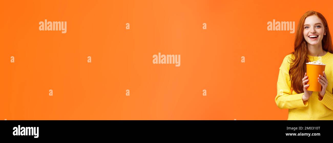 Cheerful cute redhead curly girlfriend holding popcorn chat with