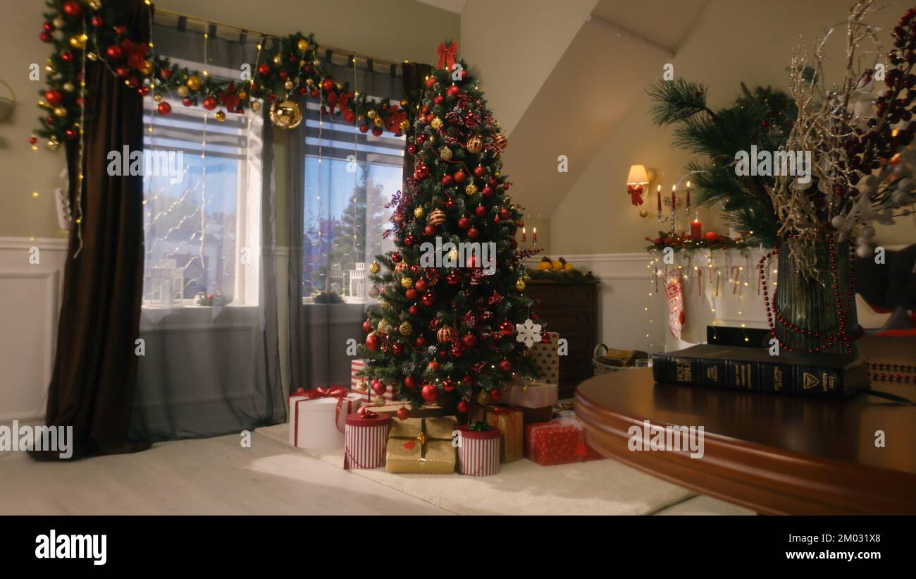 Tree with balls, toys, flashing lights, wrapped gifts and present boxes stands in living room. Christmas and New Year festive interior decoration. Atmosphere in cozy apartment on winter holidays. Stock Photo