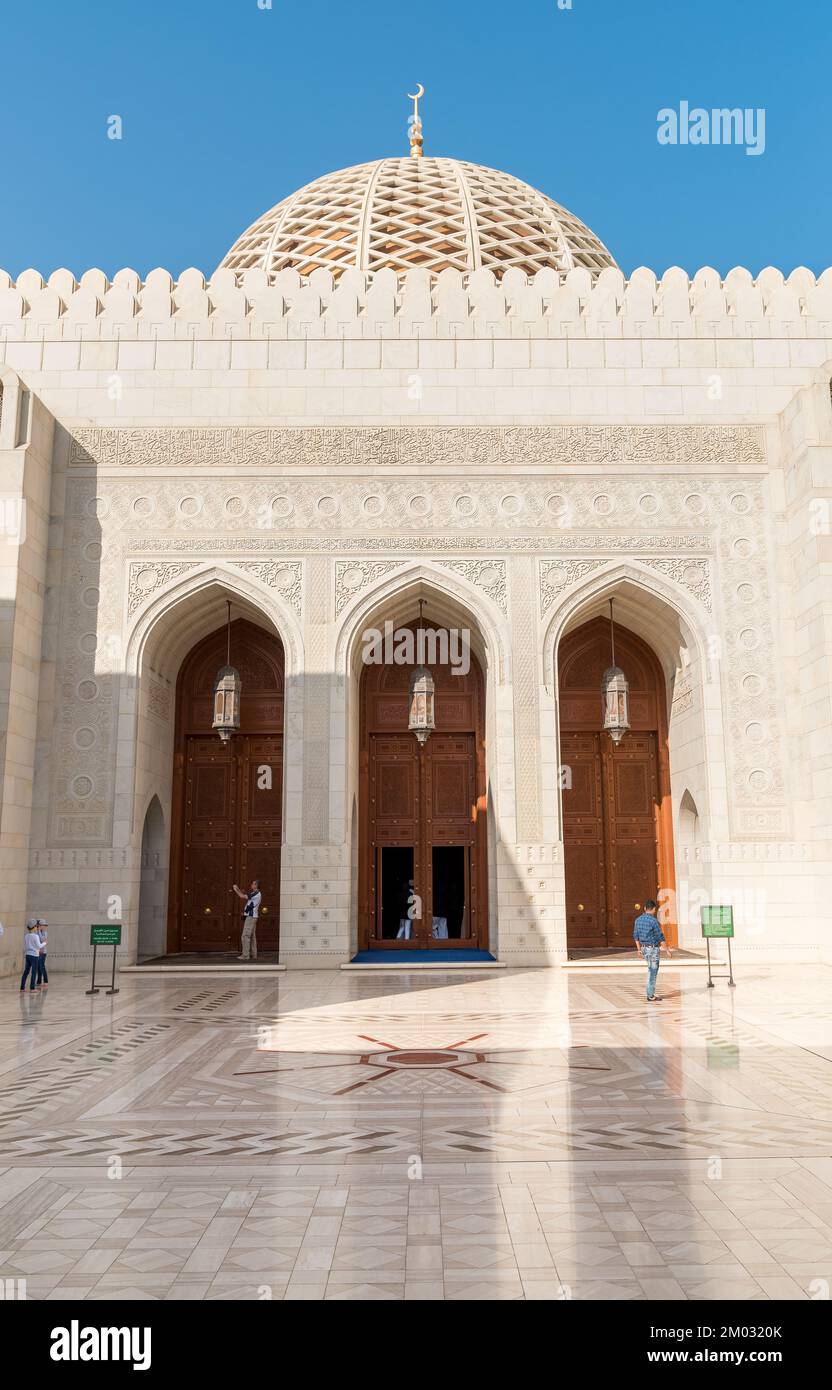 Muscat, Oman, Middle East - February 10, 2020: Arched gates and carved wooden doors leading to the Sultan Qaboos Grand Mosque. Stock Photo