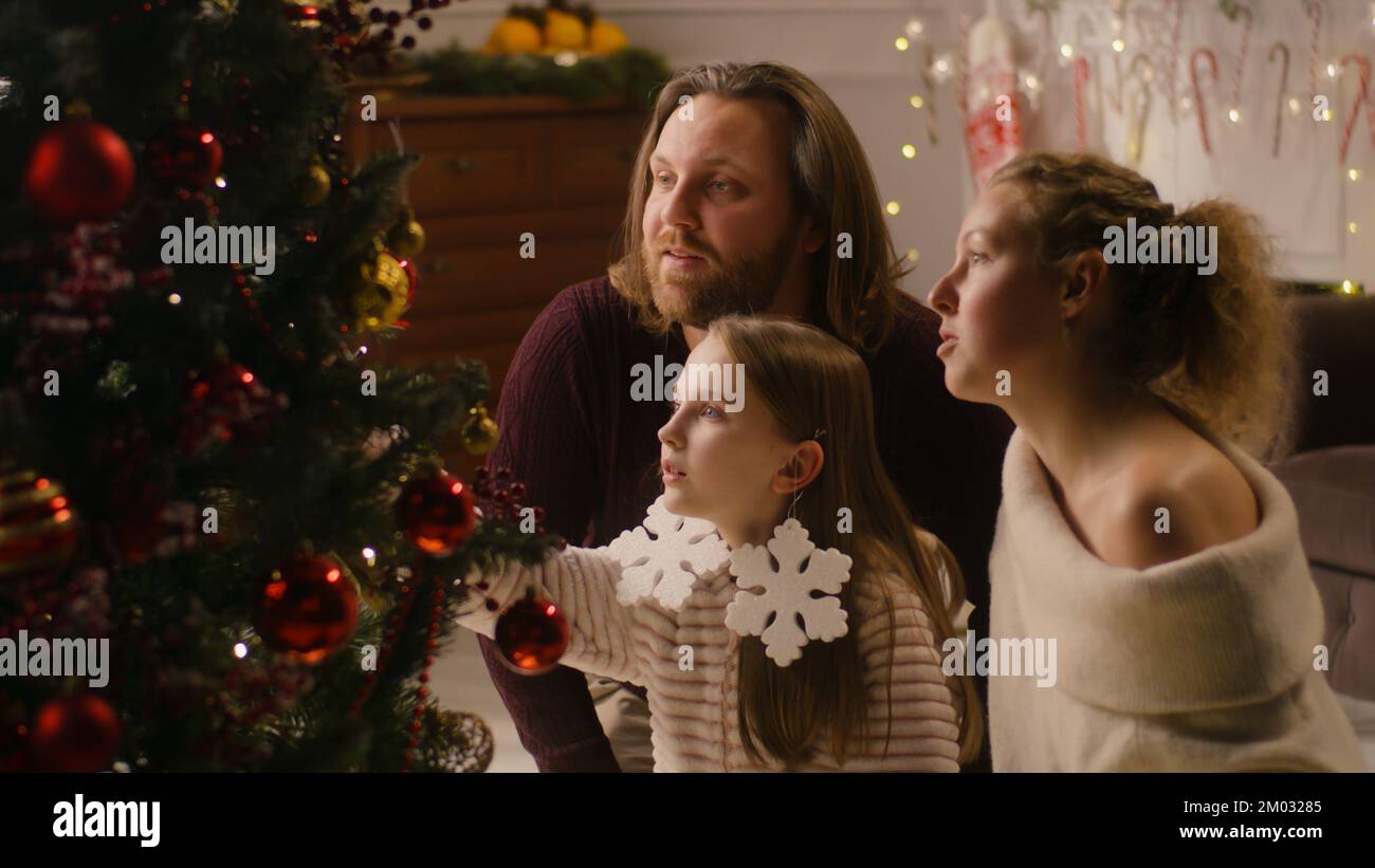Family sitting together in living room and decorating Christmas tree