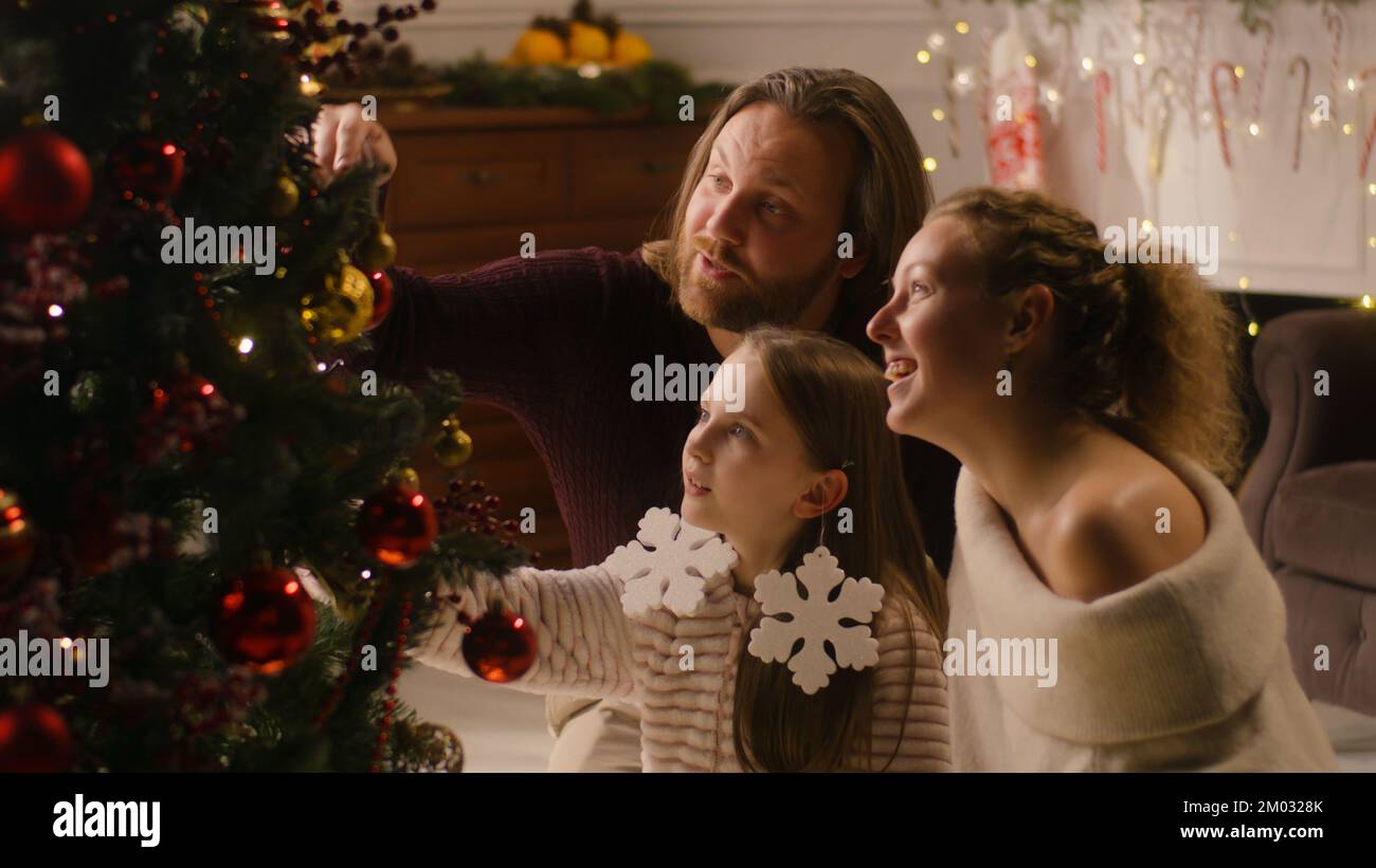 Family sitting together in living room and decorating Christmas tree