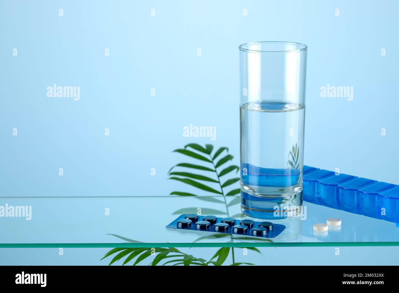 Health care composition with pills, glass of pure water and container for pills on glass shelf with copy space. Flu season and no virus concept. Natur Stock Photo