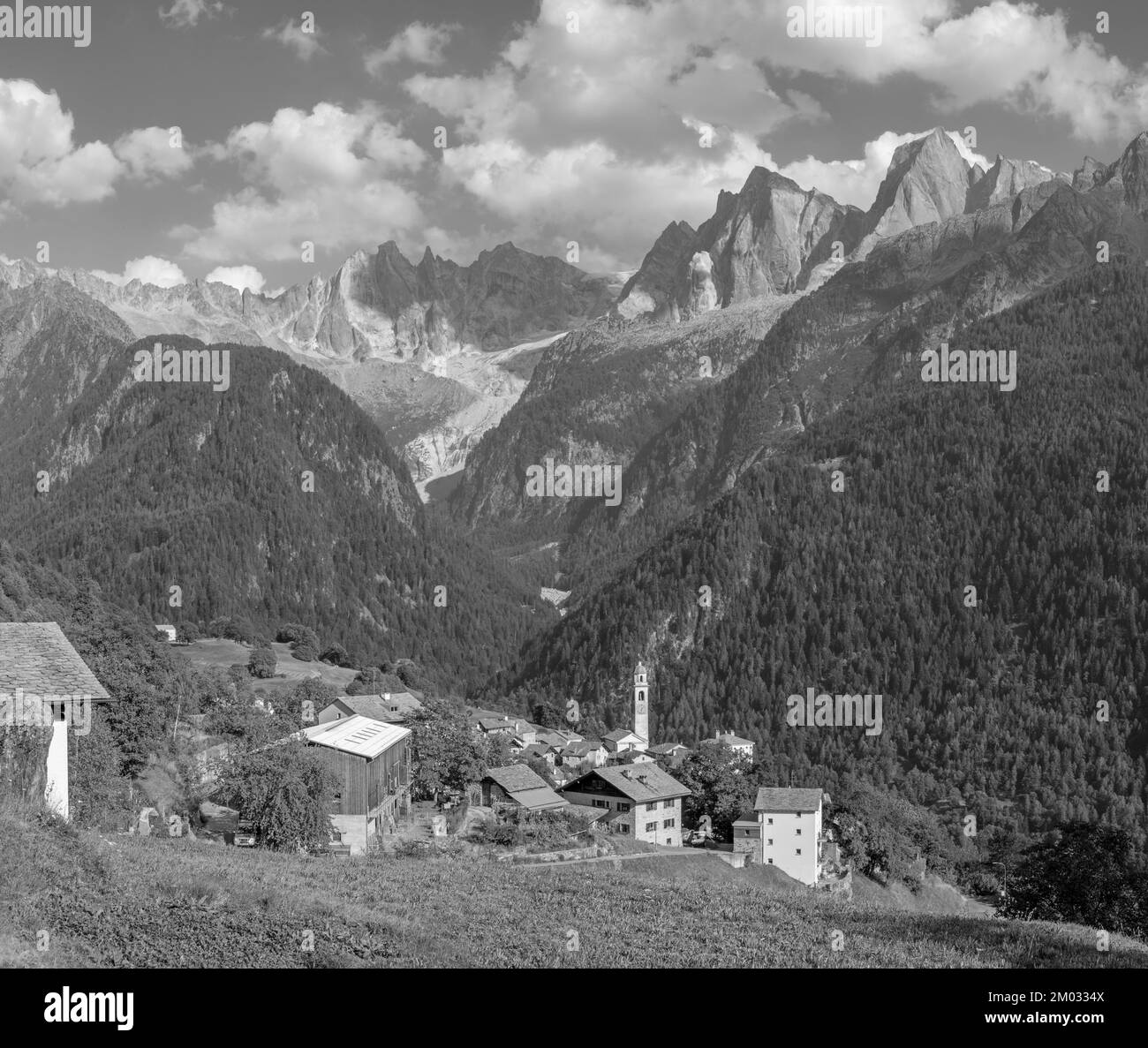 The Soglio village and Piz Badile, Pizzo Cengalo, and Sciora peaks in the Bregaglia range - Switzerland. Stock Photo