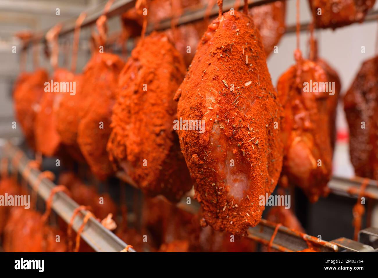 pieces of pork delicacies in paprika and spices are hung on a metal