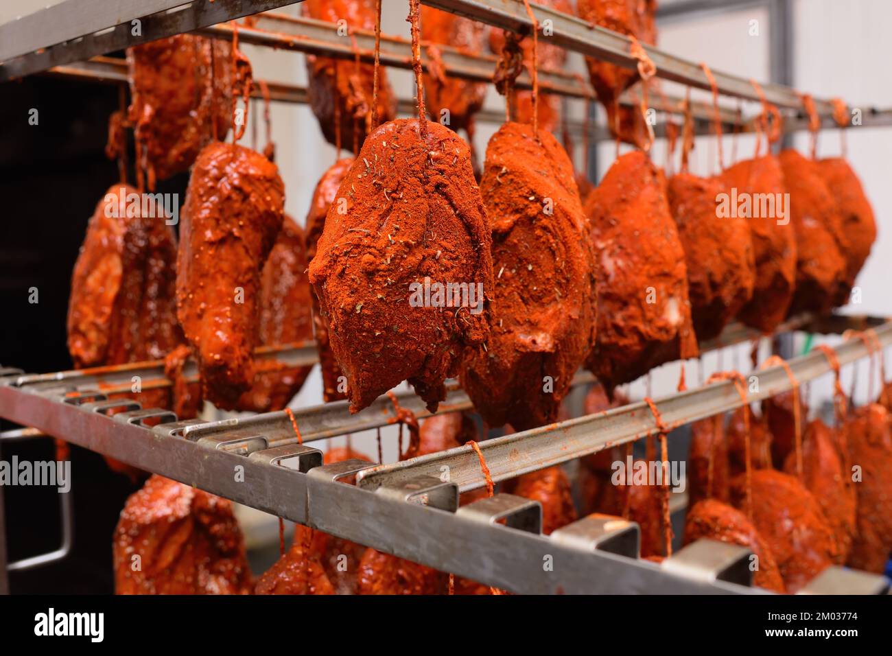 pieces of pork delicacies in paprika and spices are hung on a metal