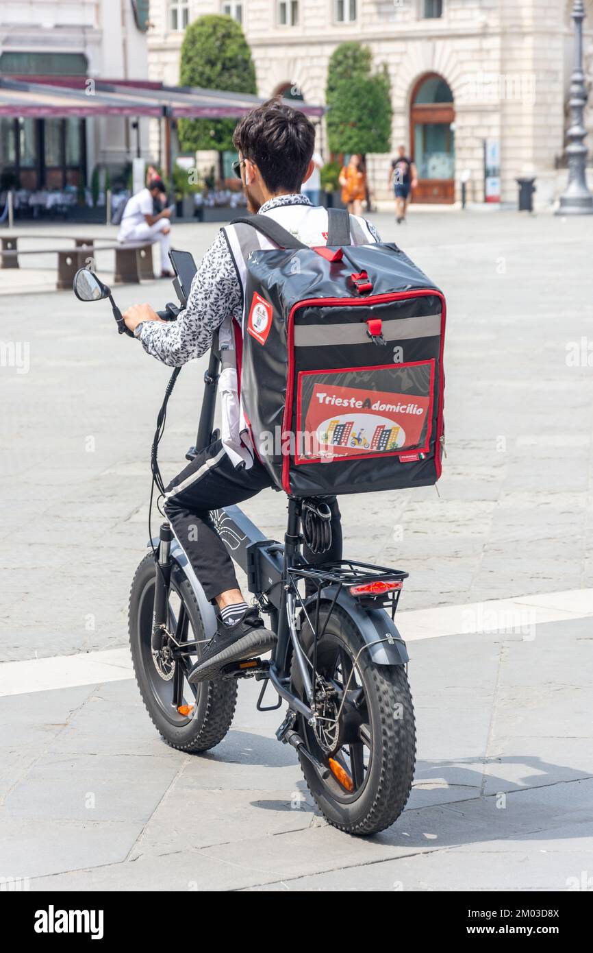 'Trieste A Domicilio' electric bike delivery driver, Piazza della Borsa, Trieste, Friuli Venezia Giulia Region, Italy Stock Photo