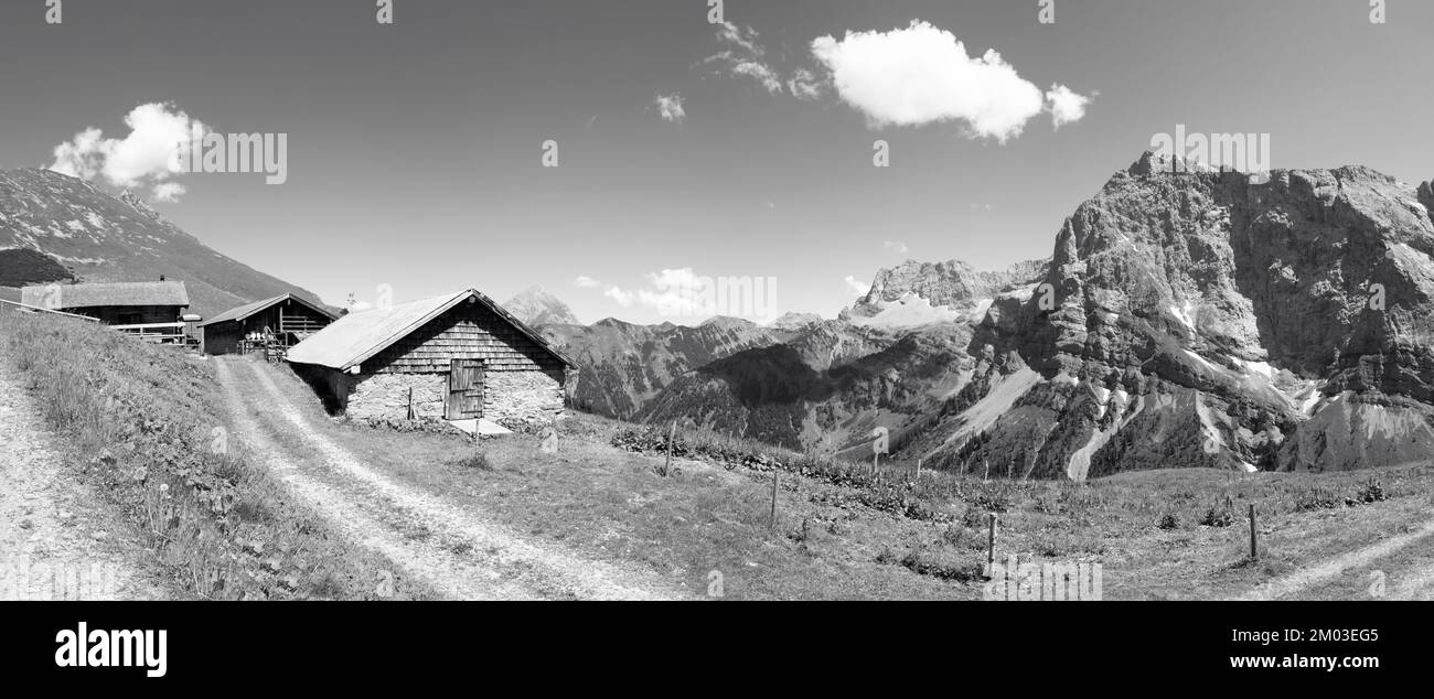 The north walls of Karwendel mountains -  Hahnkampl and Lamsen spitze peaks (right) and chalets over the Enger valley. Stock Photo