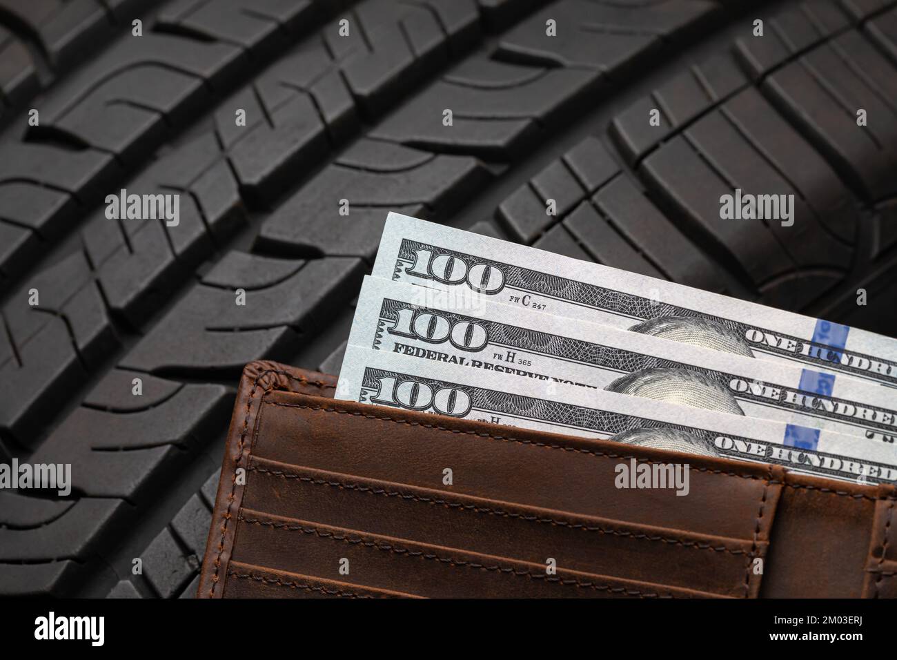 Automobile car tire with cash money in wallet. Auto repair, vehicle maintenance and buying new tires concept Stock Photo