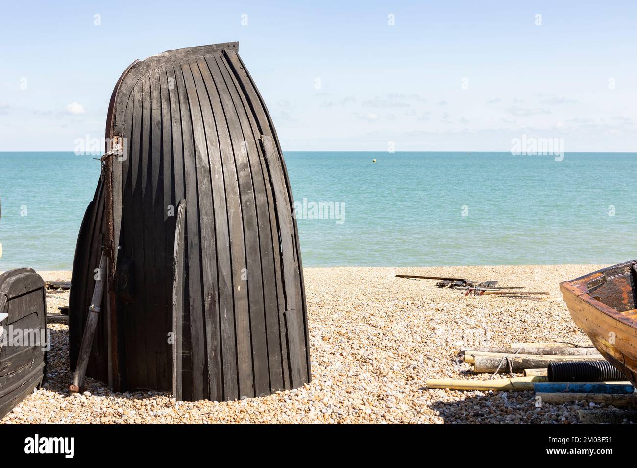 black boat hull on a pebble beach converted into a fishing storage area
