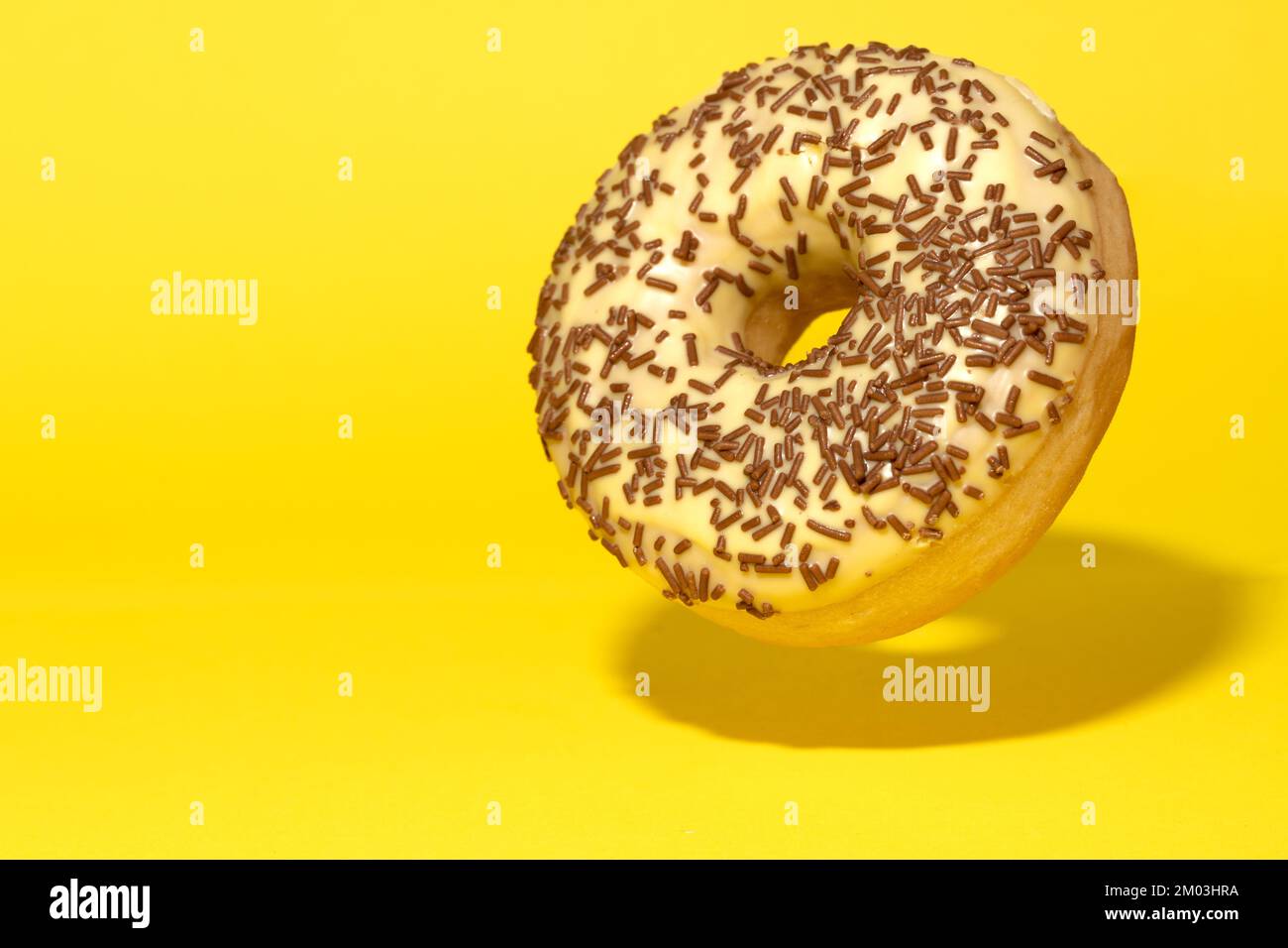 Levitating yellow donut on a yellow background. Creative sweet concept Stock Photo