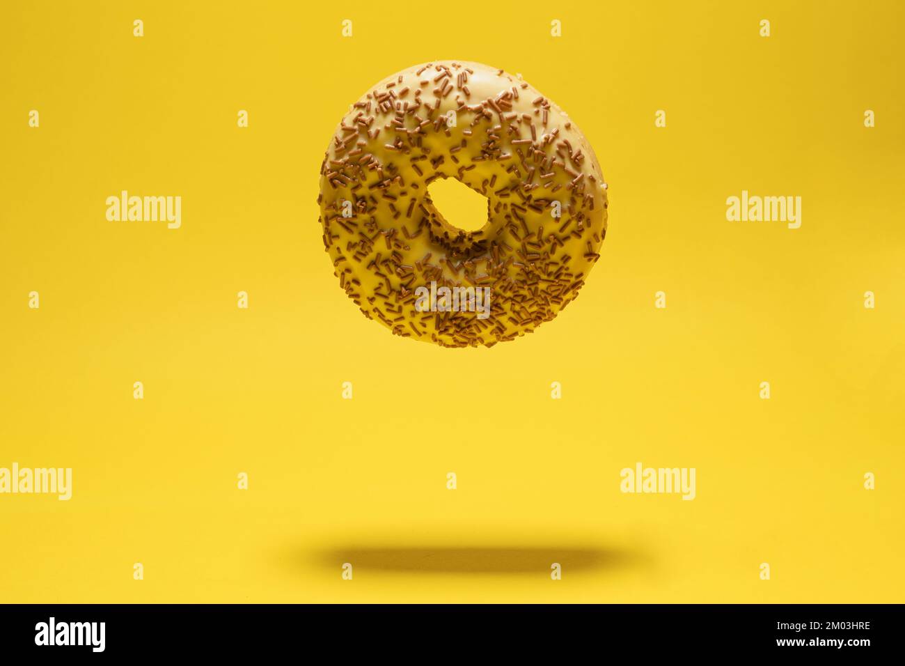 Levitating yellow donut on a yellow background. Creative sweet concept Stock Photo