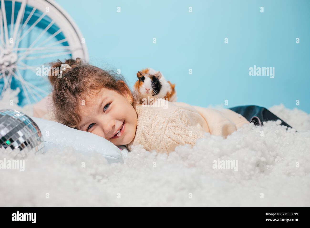 Laughing funny, merry, positive little girl getting surprise present box, sitting on soft cozy cotton carpet like snow Stock Photo
