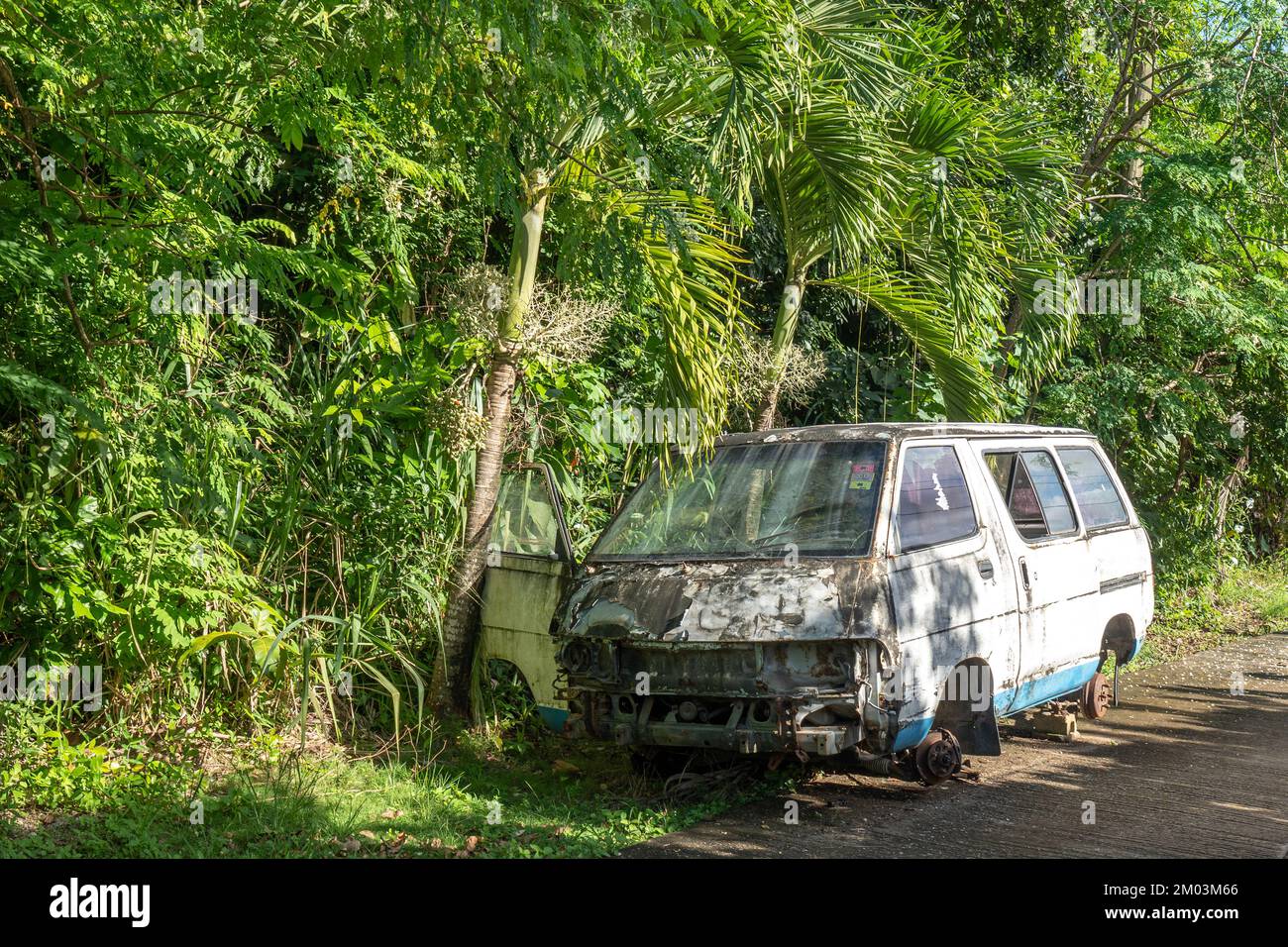 Old rusted wrecked car with no wheels abandoned on the street near