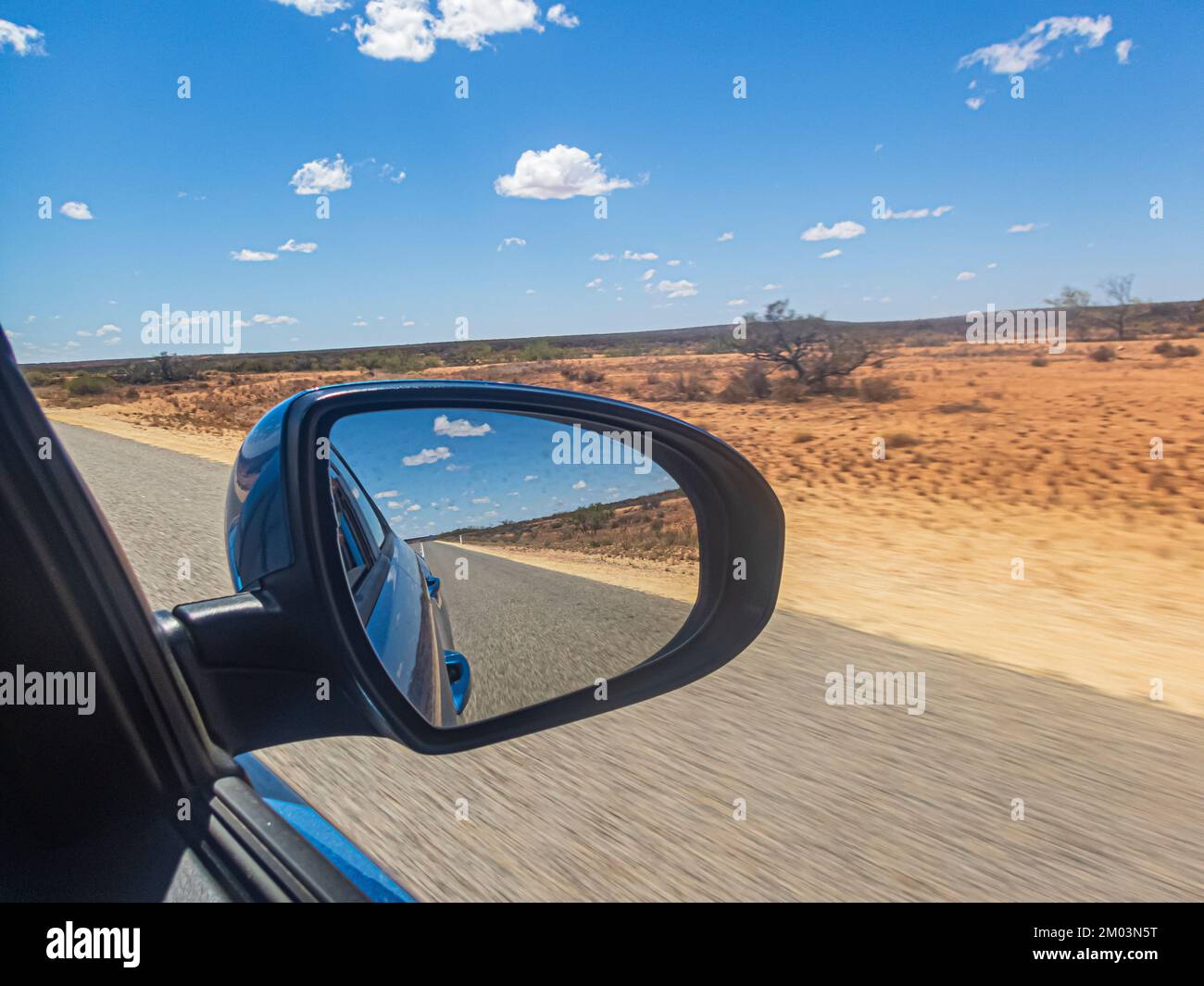 Car's side mirror with reflection against desert landscape along Coral Coast Highway in Western Australia, Australia. Stock Photo