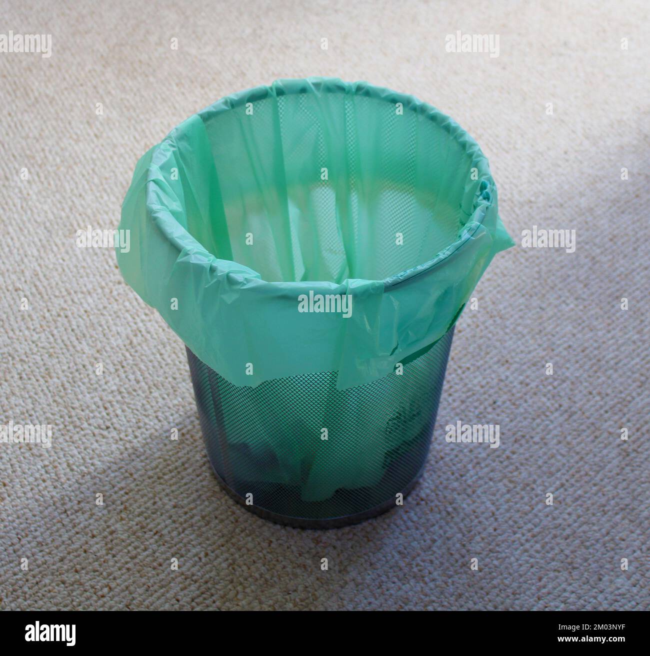 A Green Biodegradable Trash Liner in a Metal Waste Basket Stock Photo
