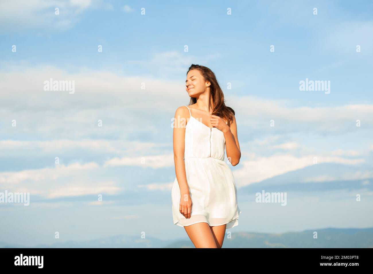 Happy Smiling Young women in white dress posing mountain top a white dress, Standing On Mountain Against Cloudy Sky, Photo Taken in the Carpathian Stock Photo