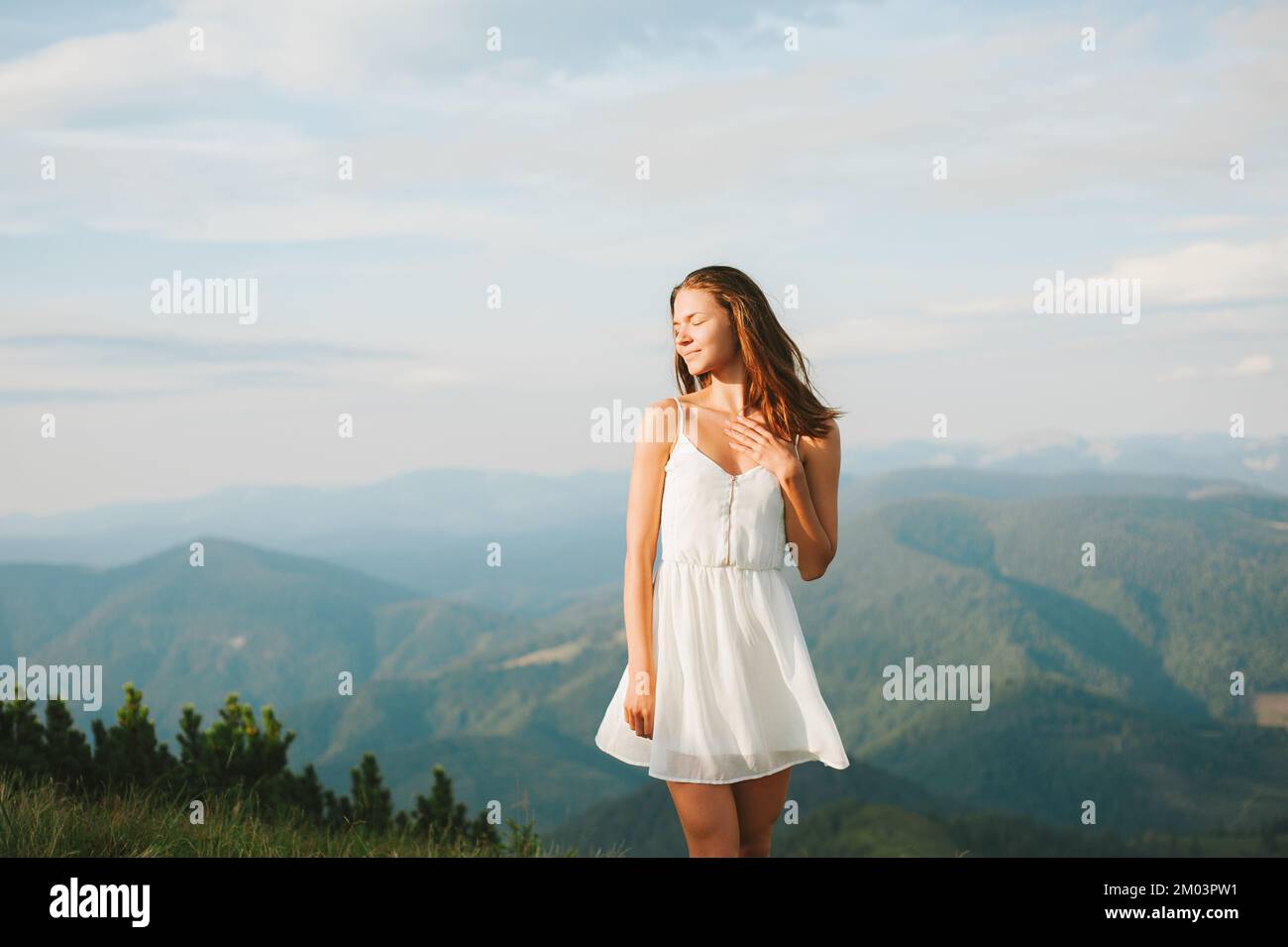 Happy Smiling Young women in white dress posing mountain top a white dress, Standing On Mountain Against Cloudy Sky, Photo Taken in the Carpathian Stock Photo
