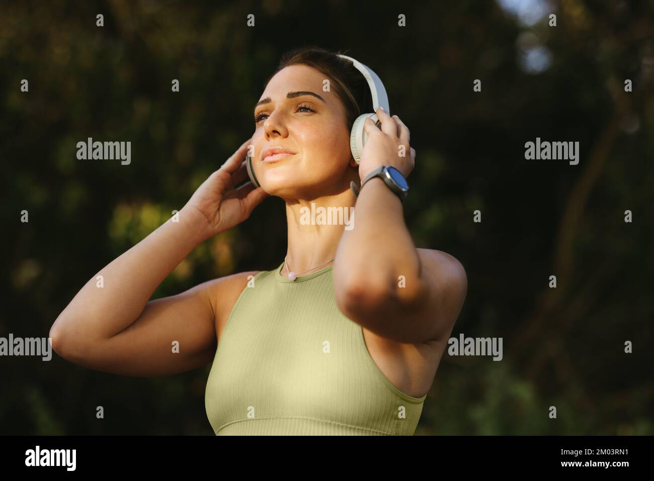 Fit woman listening to warmup music on headphones outdoors. Sportswoman preparing for a morning yoga workout. Exercising and practicing a healthy life Stock Photo