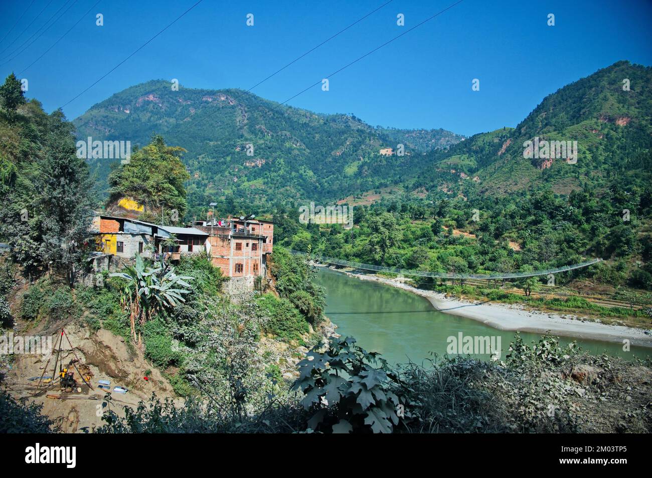 View from the bus window on the road in Nepal with the river and hanging bridge Stock Photo