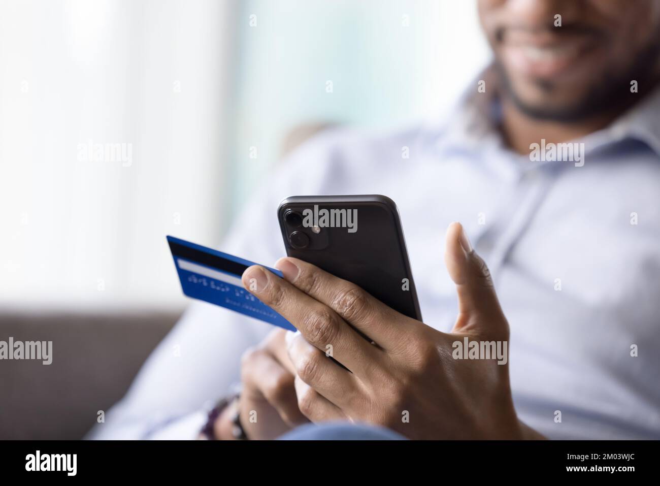Focused mobile phone user man using credit card Stock Photo