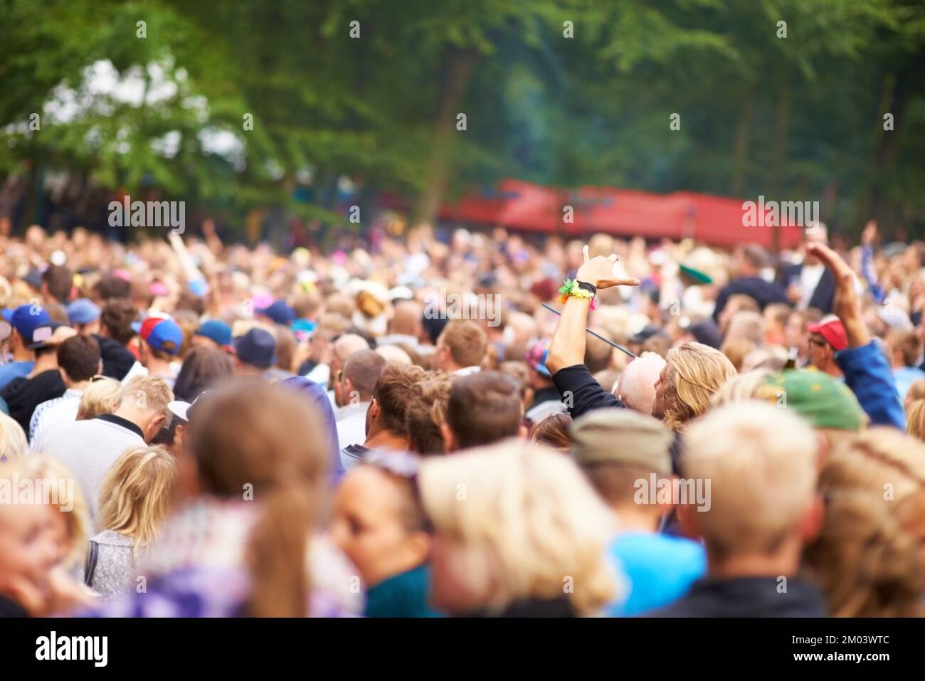 Cheering crowd. a large crowd standing outside and looking towards a stage at a music festival. Stock Photo