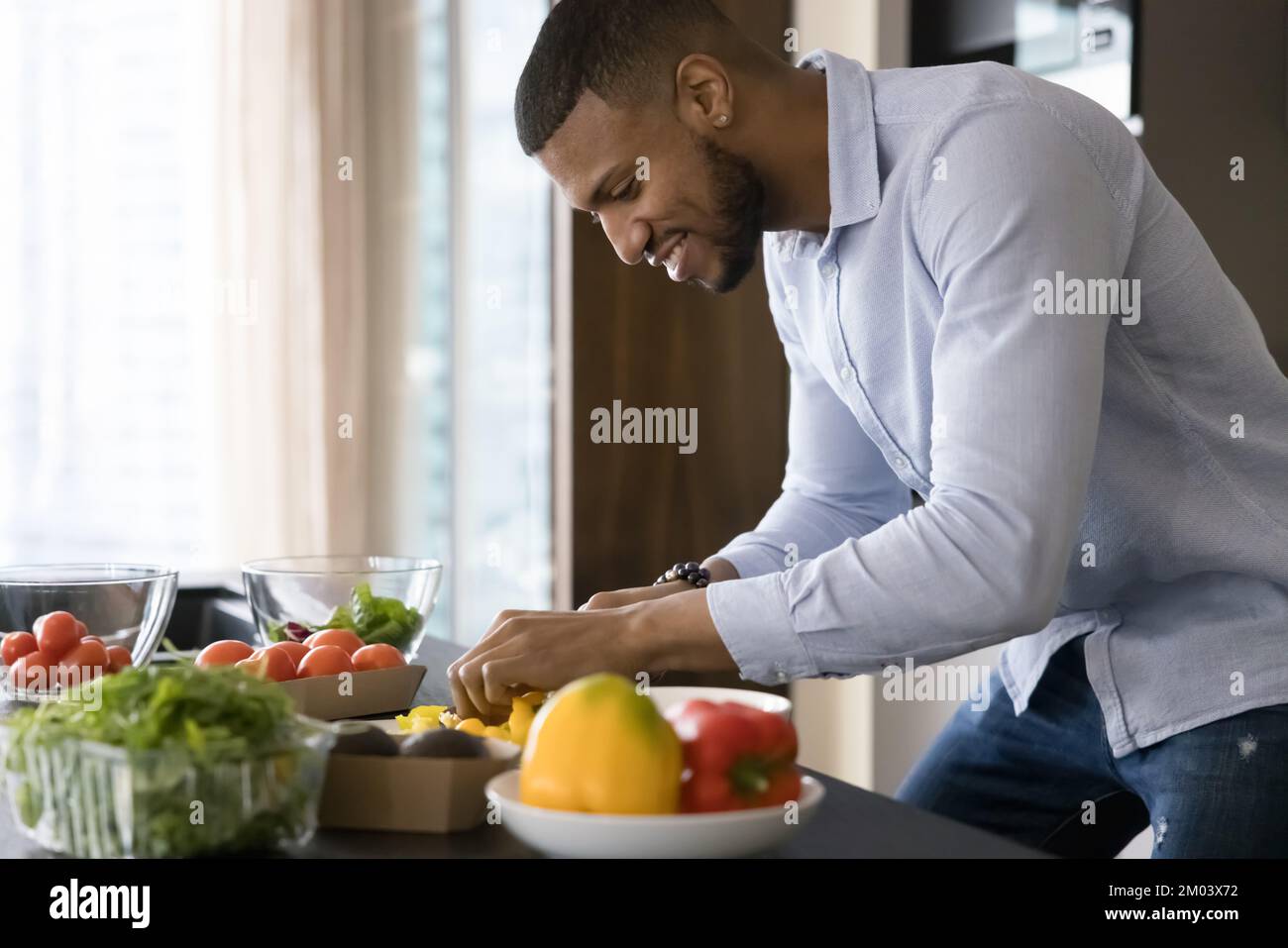 Happy handsome young African chef guy cooking vegan meal Stock Photo